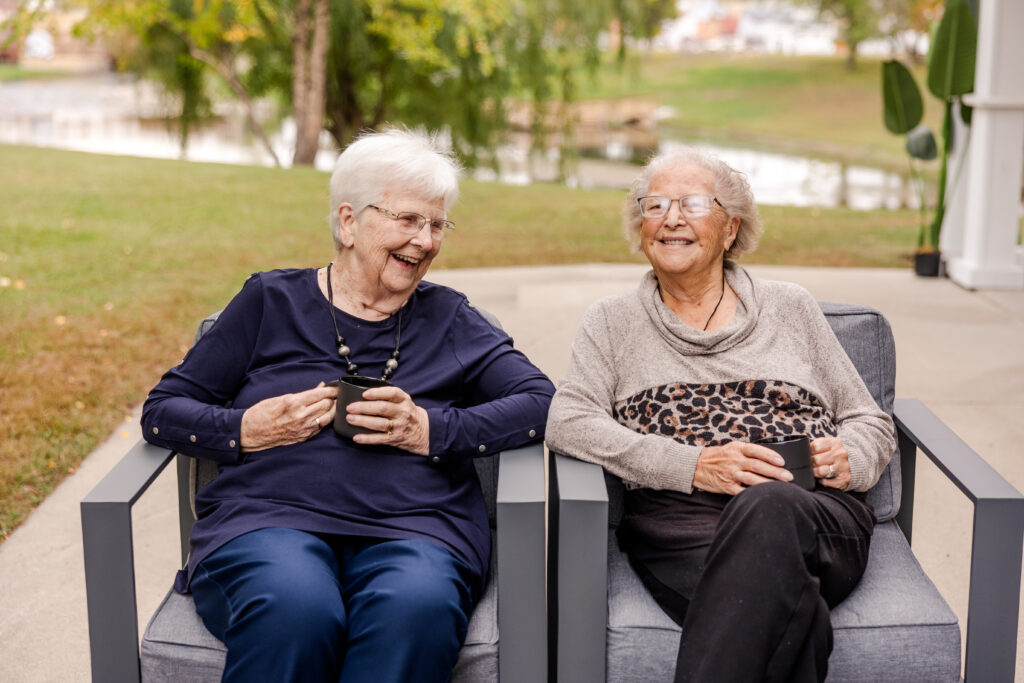 Two Residents Sitting Together Outside Smiling | Pelican Valley Senior Living